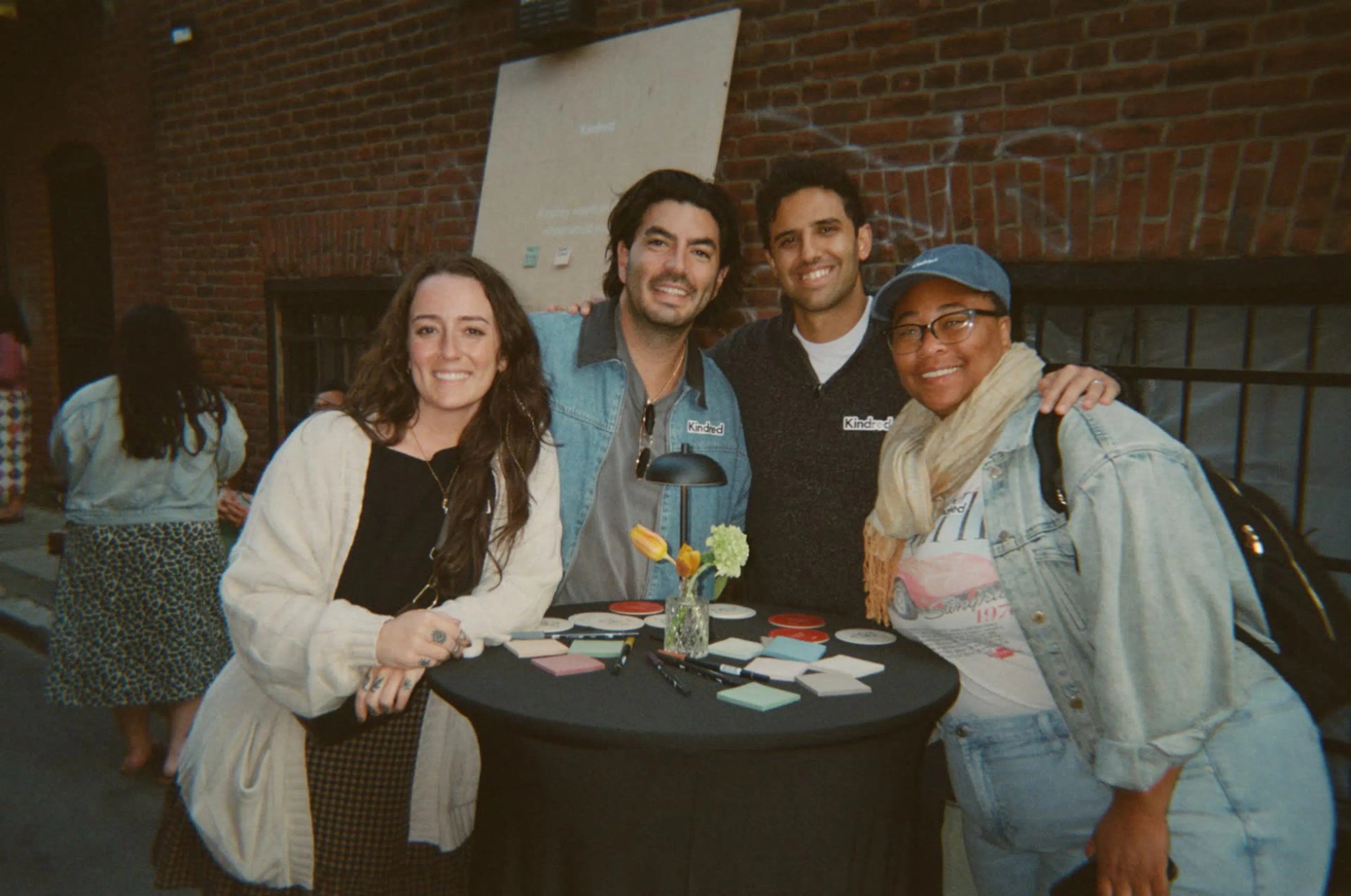 Four teammates smiling together at a Kindred block party.