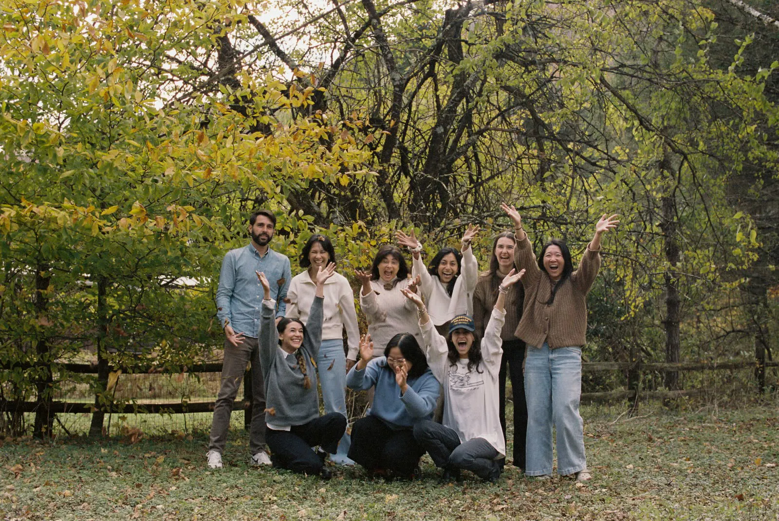 The team cheering together under autumn trees at the Catskills offsite.