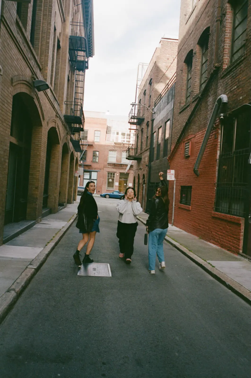 Three teammates goofing around in a sunlit San Francisco alley.