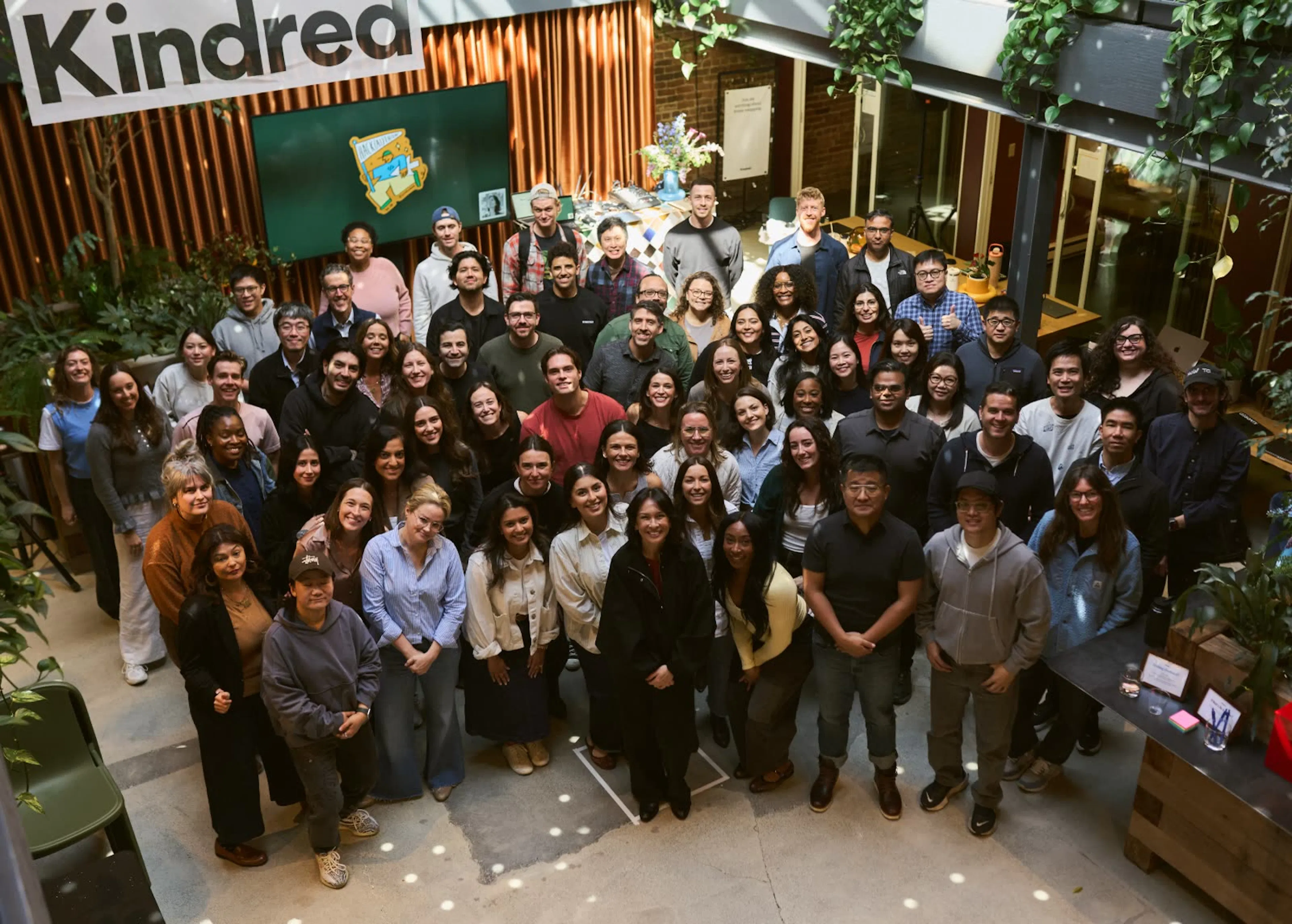 The Kindred team gathered together for a group photo under the Kindred banner at an all-hands.